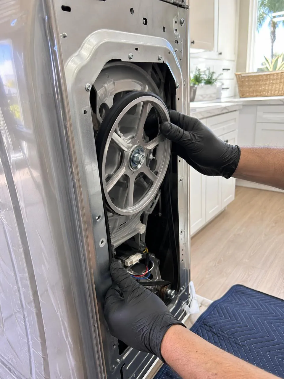 Technician replacing drive belt and motor on washer in San Diego home