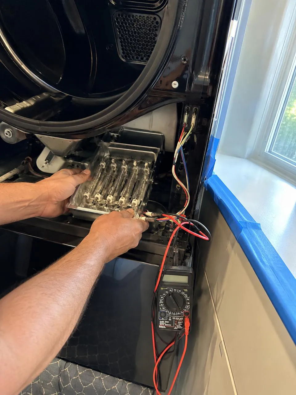 Technician testing dryer heating element with multimeter in Southern California home