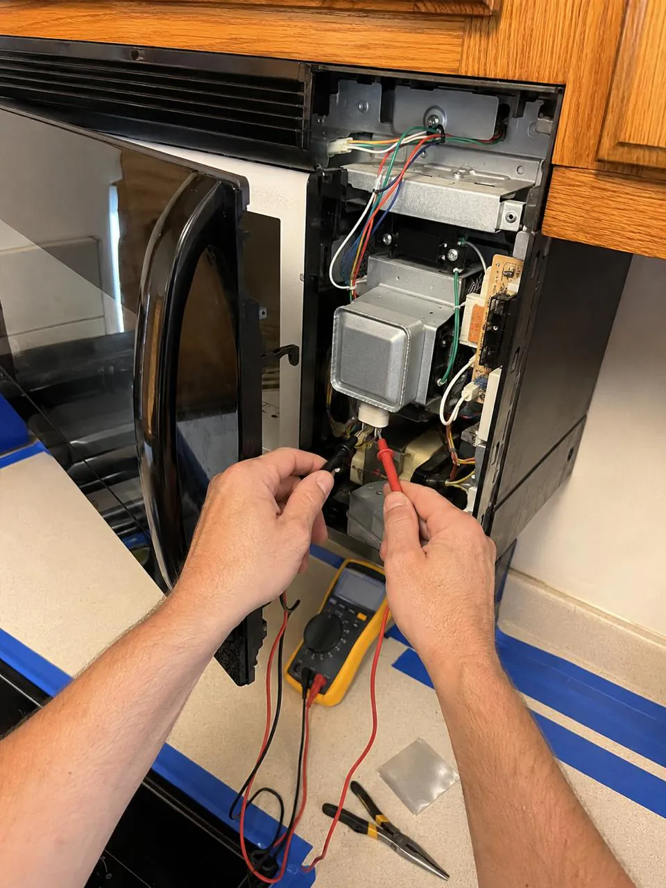 Technician testing over-the-range microwave magnetron in Southern California home