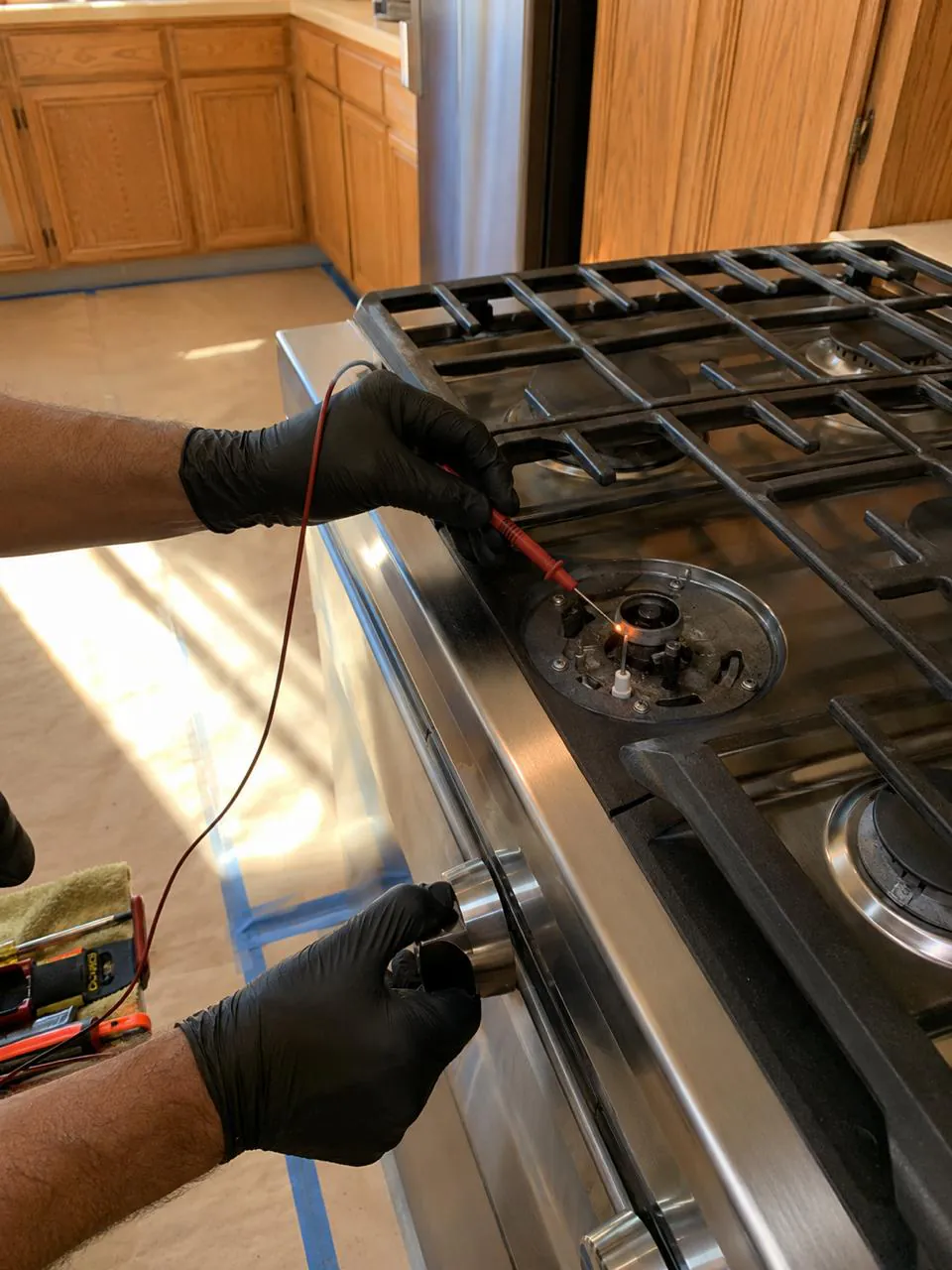 Technician testing gas cooktop burner igniter in a San Diego home kitchen