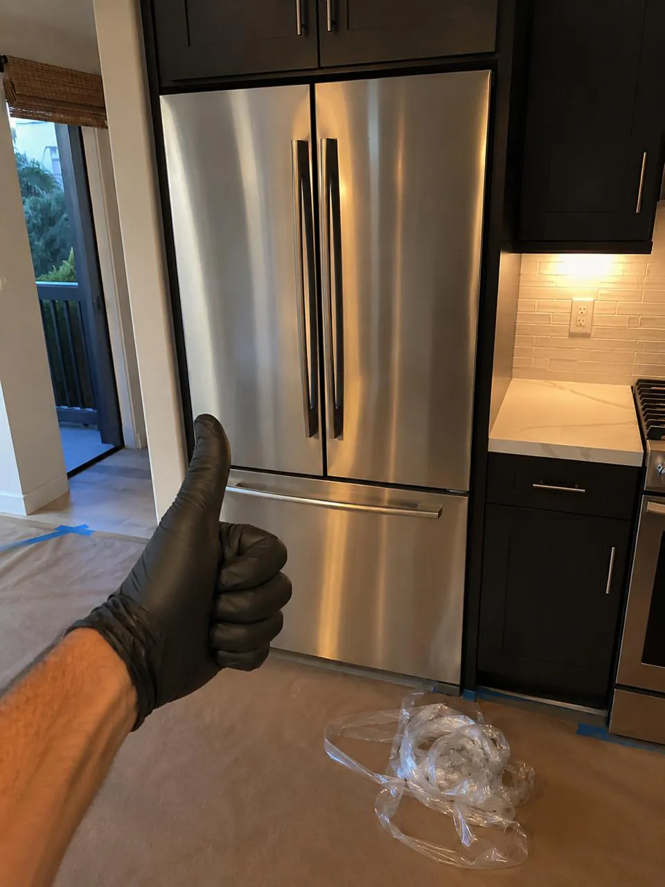 Technician testing French-door refrigerator after repair in Southern California home