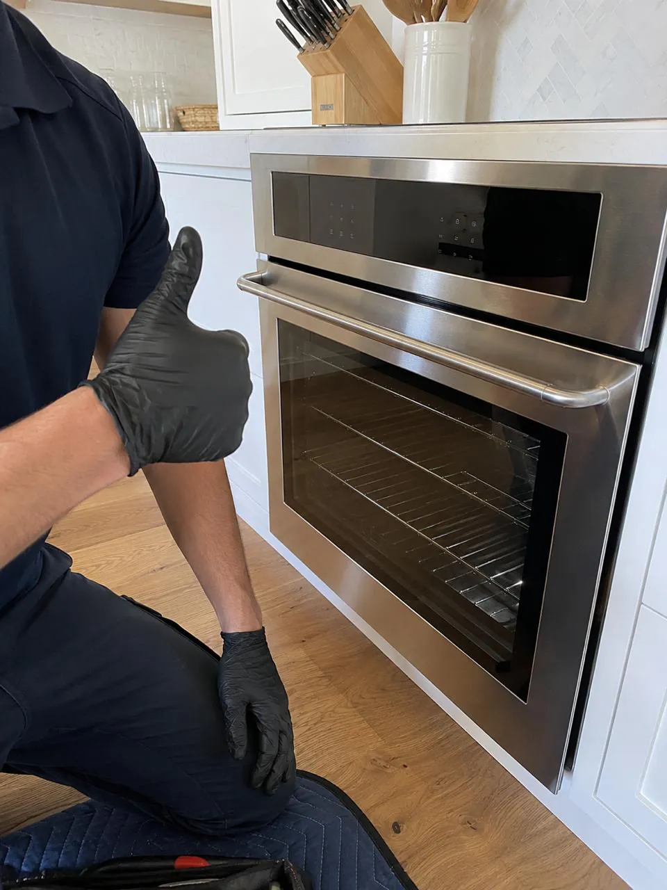 Technician completing a wall oven repair in a bright kitchen