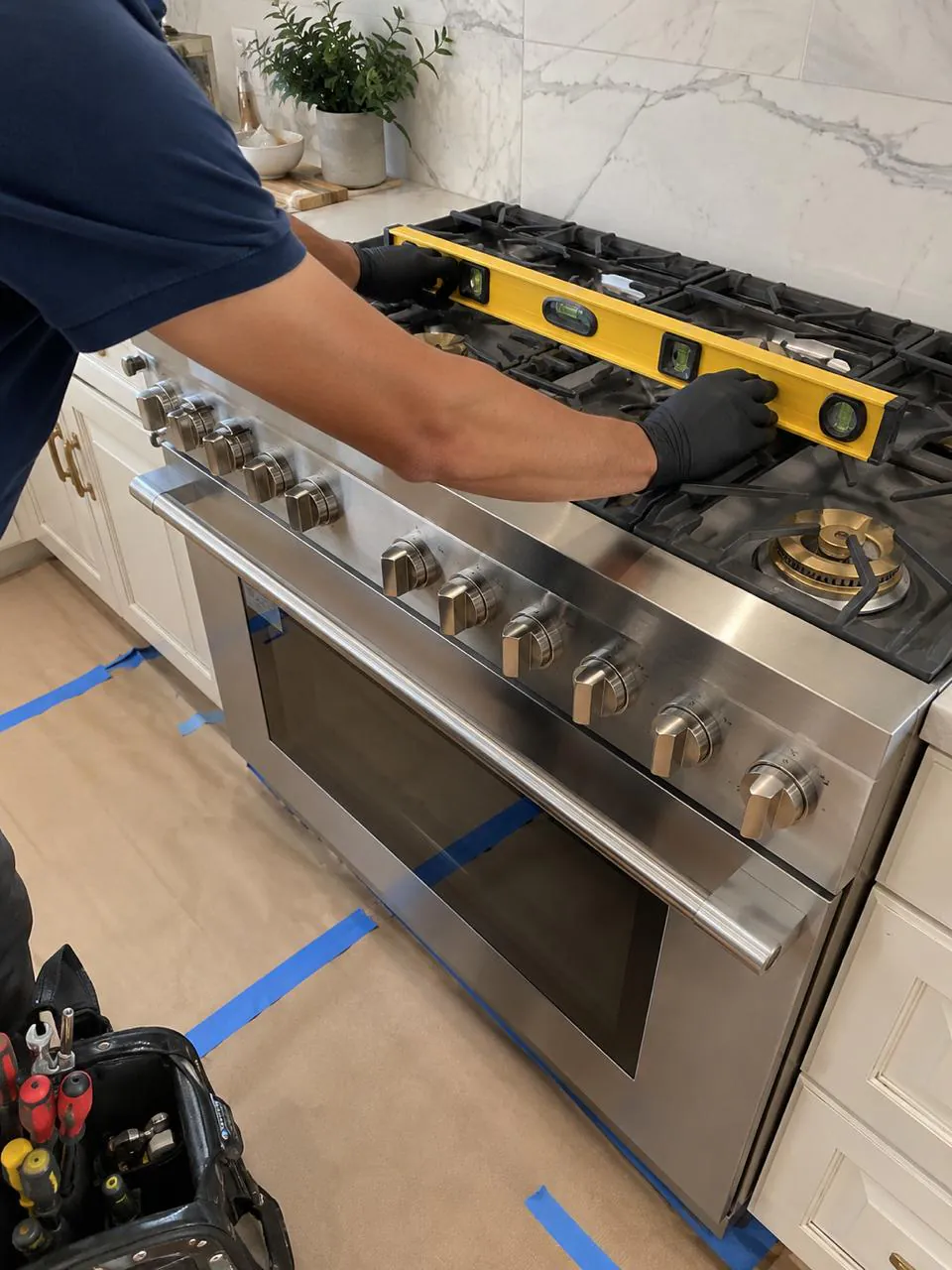 Technician servicing a stainless gas range in a San Diego home