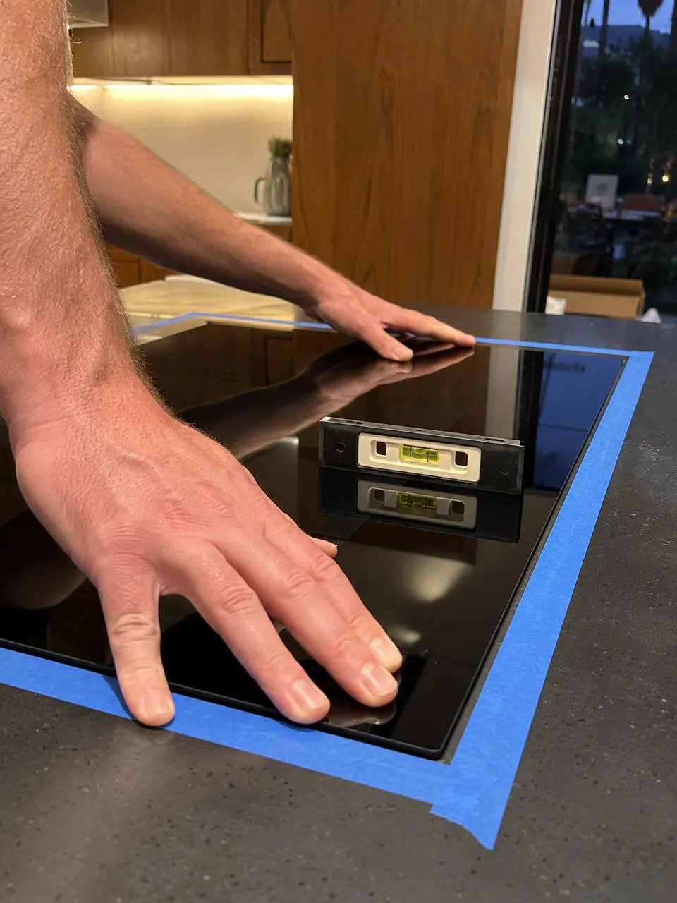 Technician servicing a black induction cooktop in a San Diego home